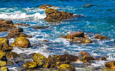 Plaj kumsalı turkuvaz mavi su kayaları kaya kayaları palmiye ağaçları büyük sörfçü dalgaları ve plaj manzarası Playa Manzanillo ve Puerto Angelito Puerto Escondido Oaxaca Meksika.
