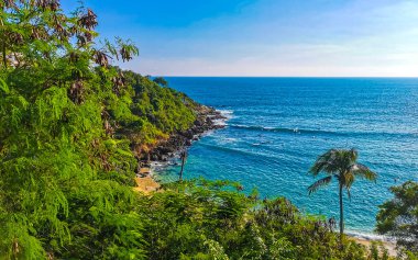 Kumsal turkuvaz mavi su kayaları kaya kayaları palmiye ağaçları büyük sörfçü dalgaları ve Puerto Escondido Oaxaca 'daki Playa Carrizalillo plajı manzarası.