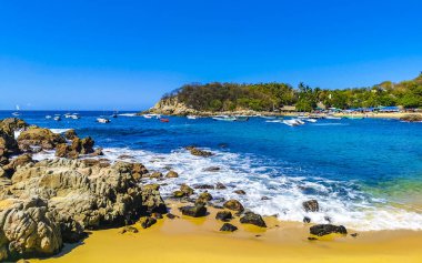 Puerto Escondido Oaxaca Meksika 25. Mart 2023 Limanı ve palmiye ağaçlı tekneler insanlara şemsiye ve güneş panzeleri veriyor Puerto Escondido Oaxaca Meksika 'daki tropikal Meksika plajlarında..