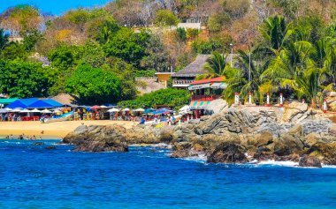 Puerto Escondido Oaxaca Meksika 25. Mart 2023 Palmiye ağaçları insanlar Zicatela Puerto Escondido Oaxaca Meksika 'daki tropikal Meksika plajında şemsiye ve güneş panzeleri tekneleri.