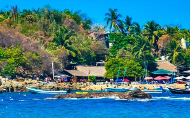 Puerto Escondido Oaxaca Meksika 25. Mart 2023 Limanı ve palmiye ağaçlı tekneler insanlara şemsiye ve güneş panzeleri veriyor Puerto Escondido Oaxaca Meksika 'daki tropikal Meksika plajlarında..