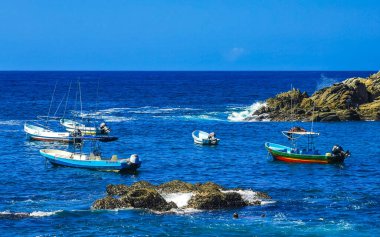 Puerto Escondido Oaxaca Meksika 25. Mart 2023 Limanı ve palmiye ağaçlı tekneler insanlara şemsiye ve güneş panzeleri veriyor Puerto Escondido Oaxaca Meksika 'daki tropikal Meksika plajlarında..