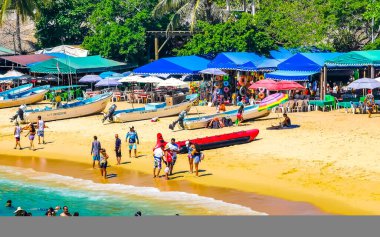 Puerto Escondido Oaxaca Meksika 25. Mart 2023 Palmiye ağaçları insanlar Zicatela Puerto Escondido Oaxaca Meksika 'daki tropikal Meksika plajında şemsiye ve güneş panzeleri tekneleri.