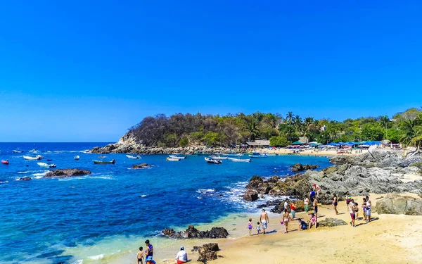 Puerto Escondido Oaxaca Meksika 25. Mart 2023 Palmiye ağaçları insanlar Zicatela Puerto Escondido Oaxaca Meksika 'daki tropikal Meksika plajında şemsiye ve güneş panzeleri tekneleri.