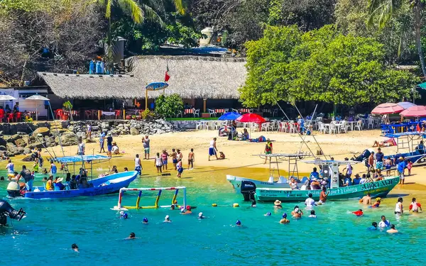 stock image Puerto Escondido Oaxaca Mexico 25. March 2023 Palm trees people boats parasols umbrellas and sun loungers at the tropical mexican beach in Zicatela Puerto Escondido Oaxaca Mexico.