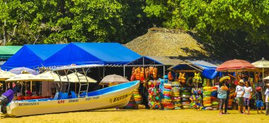 Puerto Escondido Oaxaca Meksika 25. Mart 2023 Limanı ve palmiye ağaçlı tekneler insanlara şemsiye ve güneş panzeleri veriyor Puerto Escondido Oaxaca Meksika 'daki tropikal Meksika plajlarında..
