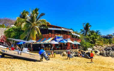 Puerto Escondido Oaxaca Meksika 25. Mart 2023 Limanı ve palmiye ağaçlı tekneler insanlara şemsiye ve güneş panzeleri veriyor Puerto Escondido Oaxaca Meksika 'daki tropikal Meksika plajlarında..