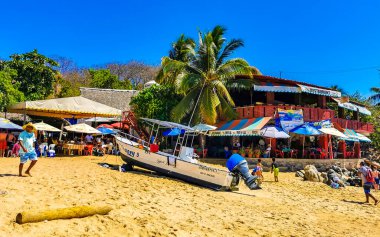 Puerto Escondido Oaxaca Meksika 25. Mart 2023 Limanı ve palmiye ağaçlı tekneler insanlara şemsiye ve güneş panzeleri veriyor Puerto Escondido Oaxaca Meksika 'daki tropikal Meksika plajlarında..