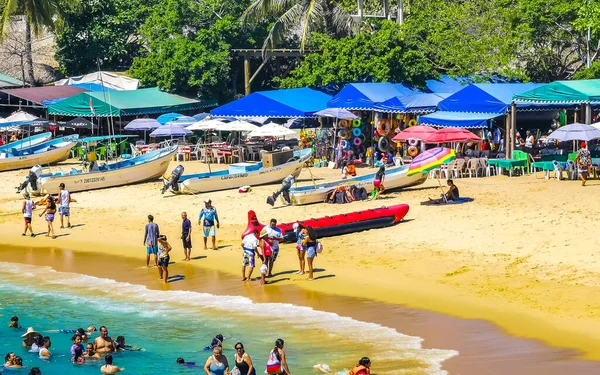 stock image Puerto Escondido Oaxaca Mexico 25. March 2023 Palm trees people boats parasols umbrellas and sun loungers at the tropical mexican beach in Zicatela Puerto Escondido Oaxaca Mexico.