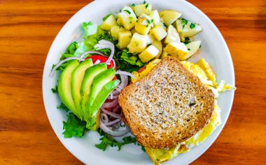 Yumurtalı tost soğanlı avokado salatası ve beyaz tabakta patates Zicatela Puerto Escondido Oaxaca Meksika 'da..