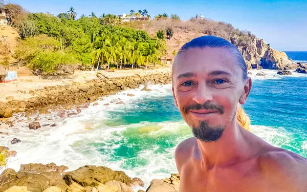 Erkek turist güzel kayalıklarla selfie çekiyor kayalar kayalar kayalar, büyük sörfçü dalgaları ve Puerto Escondido Oaxaca 'da doğal manzara..