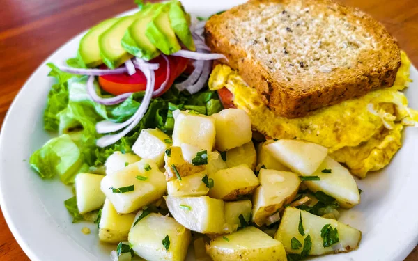 Yumurtalı tost soğanlı avokado salatası ve beyaz tabakta patates Zicatela Puerto Escondido Oaxaca Meksika 'da..