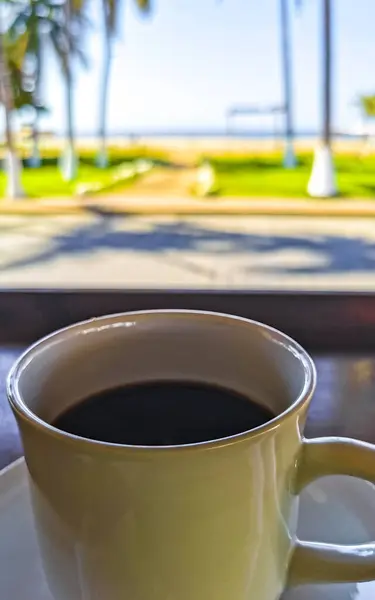 位于墨西哥瓦哈卡州Zicatela Puerto Escondido餐厅的美式黑咖啡杯 餐桌上有勺子和盘子 还有饮料 — 图库照片