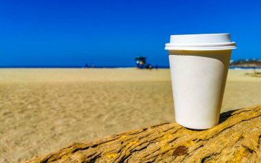 Kumsaldaki beyaz kupa El Cafecito 'ya gitmek için kahve. Kum denizi ve dalgalar Zicatela Puerto Escondido Oaxaca Meksika' nın tadını çıkarıyor..