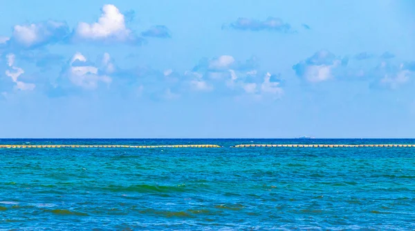 Beautiful blue and turquoise water waves ocean and yellow red orange Buoy buoys ropes and nets in the water of Playa del Carmen in Quintana Roo Mexico.