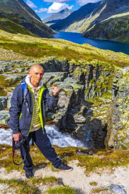 Kameralı genç gezgin fotoğrafçı ve dağlık nehir kayaları ve İskandinavya 'daki Ringbu Innlandet Norveç' teki Rondane Ulusal Parkı 'nın yürüyüş yolu ile güzel bir yaz manzarası..