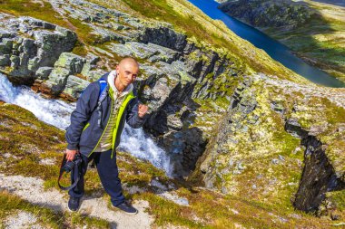 Kameralı genç gezgin fotoğrafçı ve dağlık nehir kayaları ve İskandinavya 'daki Ringbu Innlandet Norveç' teki Rondane Ulusal Parkı 'nın yürüyüş yolu ile güzel bir yaz manzarası..