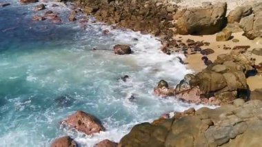 Plaj kumsalı turkuvaz mavi su kayaları kaya kayaları palmiye ağaçları büyük sörfçü dalgaları ve plaj manzarası Playa Manzanillo ve Puerto Angelito Puerto Escondido Oaxaca Meksika.
