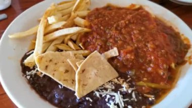Meksika omleti ve siyah fasulyeli yumurta patates ve beyaz tabakta nachos Zicatela Puerto Oaxaca Meksika 'da El Cafecito' da..