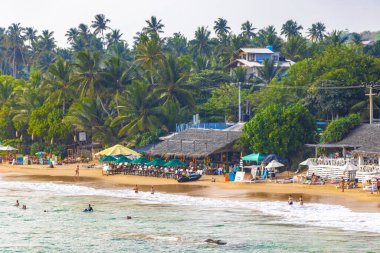 Mirissa Southern Eyaleti Sri Lanka 19. Mart 2018 Dalgalar, güneş şemsiyeleri ve Mirissa Sahili Sri Lanka 'da turistlerle dolu güzel bir tropikal plaj..