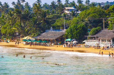 Mirissa Southern Eyaleti Sri Lanka 19. Mart 2018 Dalgalar, güneş şemsiyeleri ve Mirissa Sahili Sri Lanka 'da turistlerle dolu güzel bir tropikal plaj..