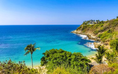 Kumsal turkuvaz mavi su kayaları kaya kayaları palmiye ağaçları büyük sörfçü dalgaları ve Puerto Escondido Oaxaca 'daki Playa Carrizalillo plajı manzarası.