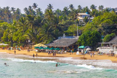 Mirissa Southern Eyaleti Sri Lanka 19. Mart 2018 Dalgalar, güneş şemsiyeleri ve Mirissa Sahili Sri Lanka 'da turistlerle dolu güzel bir tropikal plaj..