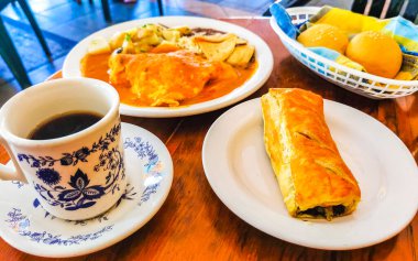 Üzerinde siyah kahve olan mavi ve beyaz fincan americano ve Zicatela Puerto Escondido Meksika 'daki El Cafecito' da hamur işi ahşap masa..