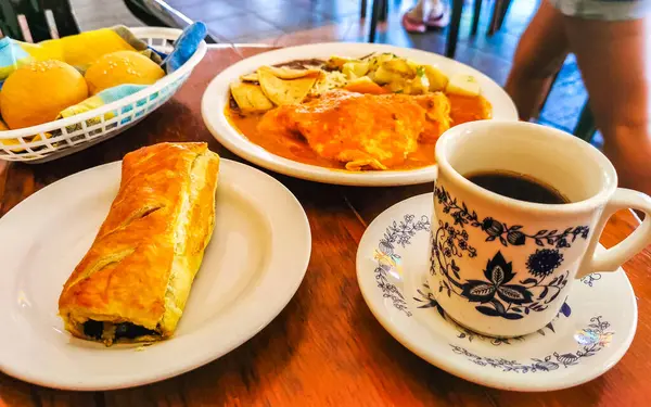 Üzerinde siyah kahve olan mavi ve beyaz fincan americano ve Zicatela Puerto Escondido Meksika 'daki El Cafecito' da hamur işi ahşap masa..