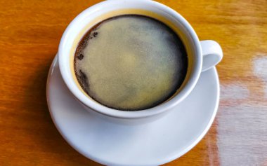 Glass cup of americano black coffee with spoon and plate on table food and drink in the restaurant PapaCharly Papa Charly in Playa del Carmen Quintana Roo Mexico.