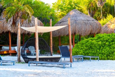 Palapa sazdan çatılar palmiye ağaçları şemsiyeler ve Playa del Carmen Meksika 'daki tropikal Meksika plajındaki sahil otelindeki güneş pansiyonları..