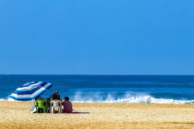 Puerto Escondido Oaxaca Meksika 13. Kasım 2022 Palmiye ağaçları Zicatela Puerto Escondido Oaxaca Mexico 'daki tropik Meksika plajındaki sahil otelindeki şemsiyeler ve güneş panzeleri..