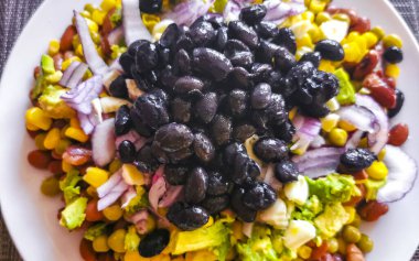 Vegetable dish soup with beans peas potatoes onions tomato and garlic on a white plate bowl with fork or spoon in Mexico.