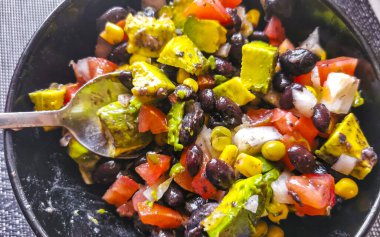 Vegetable dish soup with beans peas potatoes onions tomato and garlic on a white plate bowl with fork or spoon in Mexico.