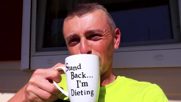 ハッピー男飲むコーヒーからホワイトカップで午前中にヴーラAtticaギリシャ — ストック動画