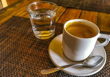 Playa del Carmen Quintana Roo Meksika 'daki restoran kafeteryasında bir bardak kahve ve kaşık tabağı ve bir bardak su..