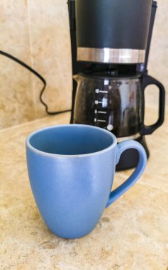 Blue coffee cups and black coffee maker from Mexico on cream background in clean kitchen.