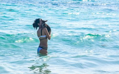 Seksi bayan güzel kadın küçük köpeğiyle birlikte Playa del Carmen Quintana Roo Mexico 'daki tropik Meksika Karayip plajında poz veriyor..