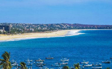 Güneş sahili kıyısı suyu ve palmiye ağacı şemsiyeli sörf dalgaları Zicatela Puerto Escondido Oaxaca 'da uçurum turizmi ve mavi gökyüzünü sallar..