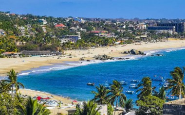 Güneş sahili kıyısı suyu ve palmiye ağacı şemsiyeli sörf dalgaları Zicatela Puerto Escondido Oaxaca 'da uçurum turizmi ve mavi gökyüzünü sallar..