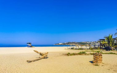 Güneş sahili kıyısı suyu ve palmiye ağacı şemsiyeli sörf dalgaları Zicatela Puerto Escondido Oaxaca 'da uçurum turizmi ve mavi gökyüzünü sallar..