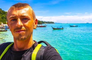 Turist gezgin erkek adam, Kireçtaşı kayalıkları, turkuaz su, Koh Phi Don adası, Ao Nang Krabi Tayland arasında uzun kuyruklu teknelerle selfie çekiyor..