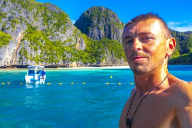 Turist erkek adam, kireçtaşından kayalar ve turkuaz mavi su Koh Phi Phi Leh adası Ao Nang Krabi Tayland arasındaki ünlü plaj gölünde selfie çekiyor..