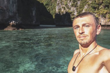 Turist erkek adam, kireçtaşından kayalar ve turkuaz mavi su Koh Phi Phi Leh adası Ao Nang Krabi Tayland arasındaki ünlü plaj gölünde selfie çekiyor..