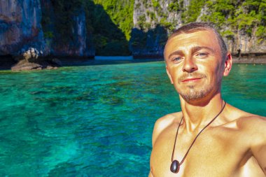 Turist erkek adam, kireçtaşından kayalar ve turkuaz mavi su Koh Phi Phi Leh adası Ao Nang Krabi Tayland arasındaki ünlü plaj gölünde selfie çekiyor..