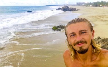 Erkek turist güzel kayalıklarla selfie çekiyor kayalar kayalar kayalar, büyük sörfçü dalgaları ve Puerto Escondido Oaxaca 'da doğal manzara..
