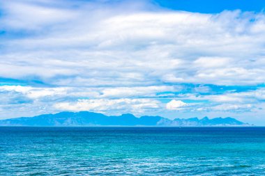 Turkuaz mavi su dağları manzaralı Long Beach manzara manzarası ve Simons Town Capetown Batı Capetown Burnu Güney Afrika Güney Afrika 'da bulutlu mavi gökyüzü.