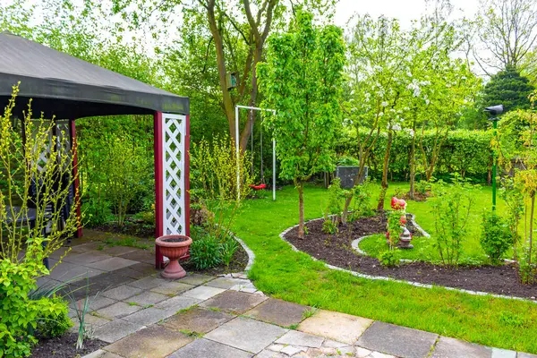 Leherheide Bremerhaven Bremen Almanya 'sında ağaçlı yeşil bahçe gübre yatakları çimenlik ve barbekü alanı.