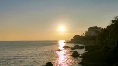 Güzel, göz kamaştırıcı, renkli ve altın sarısı günbatımı. Plajda sarı turuncu kırmızı ve büyük bir sörfçü dalgası ve kayalıklar. Zicatela Puerto Escondido Oaxaca Meksika 'da tropikal doğada uçurum manzarası..