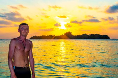 Yakışıklı erkek turist tropik cennet adası Kuramathi 'de lüks bir tatil için. Palmiye ağaçları, beyaz kum turkuaz sular ve Rasdhoo Atoll Maldivleri' nde muhteşem altın renkli günbatımı..